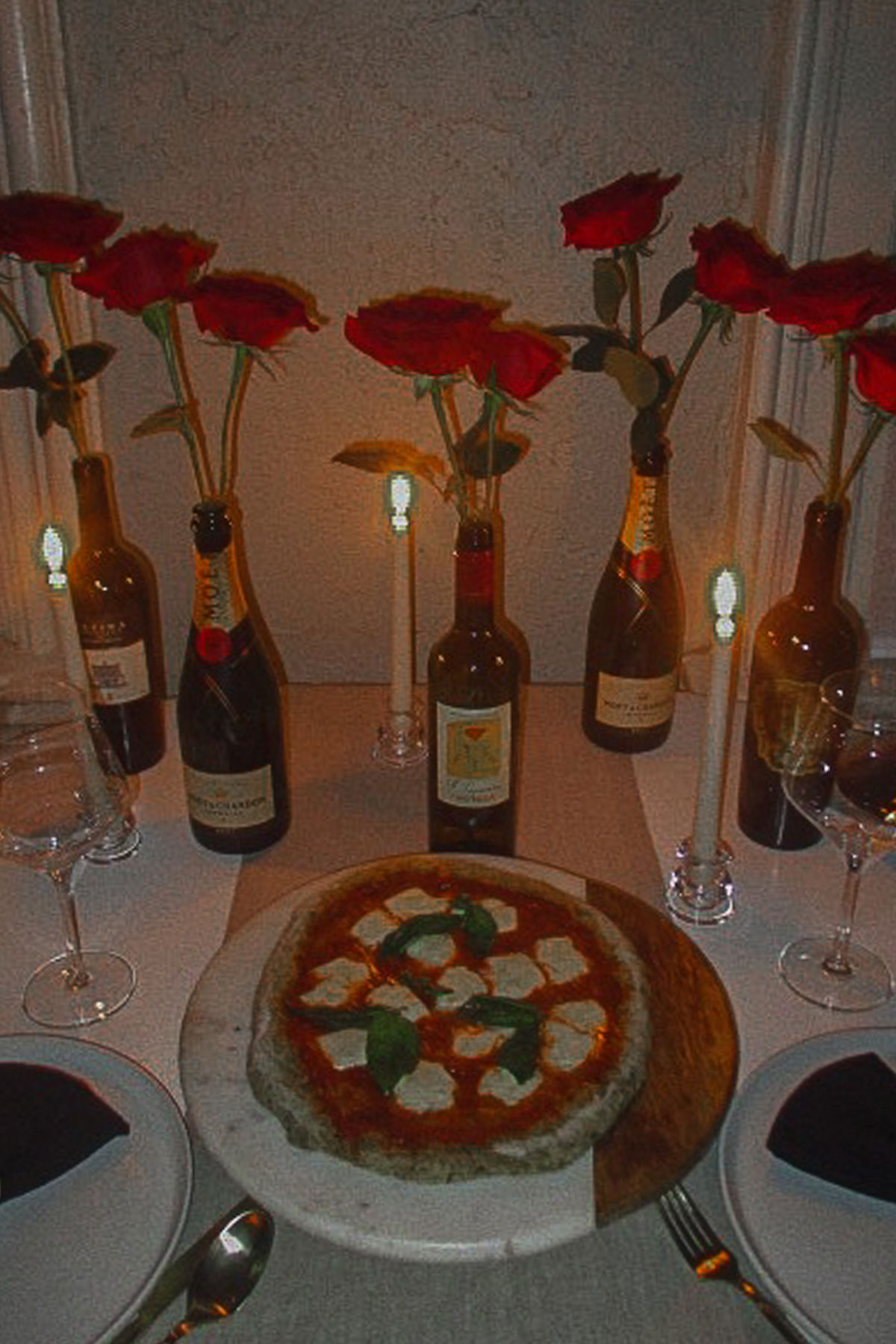 Valentine's Day dinner table with homemade pizza, candles and red rose arrangement