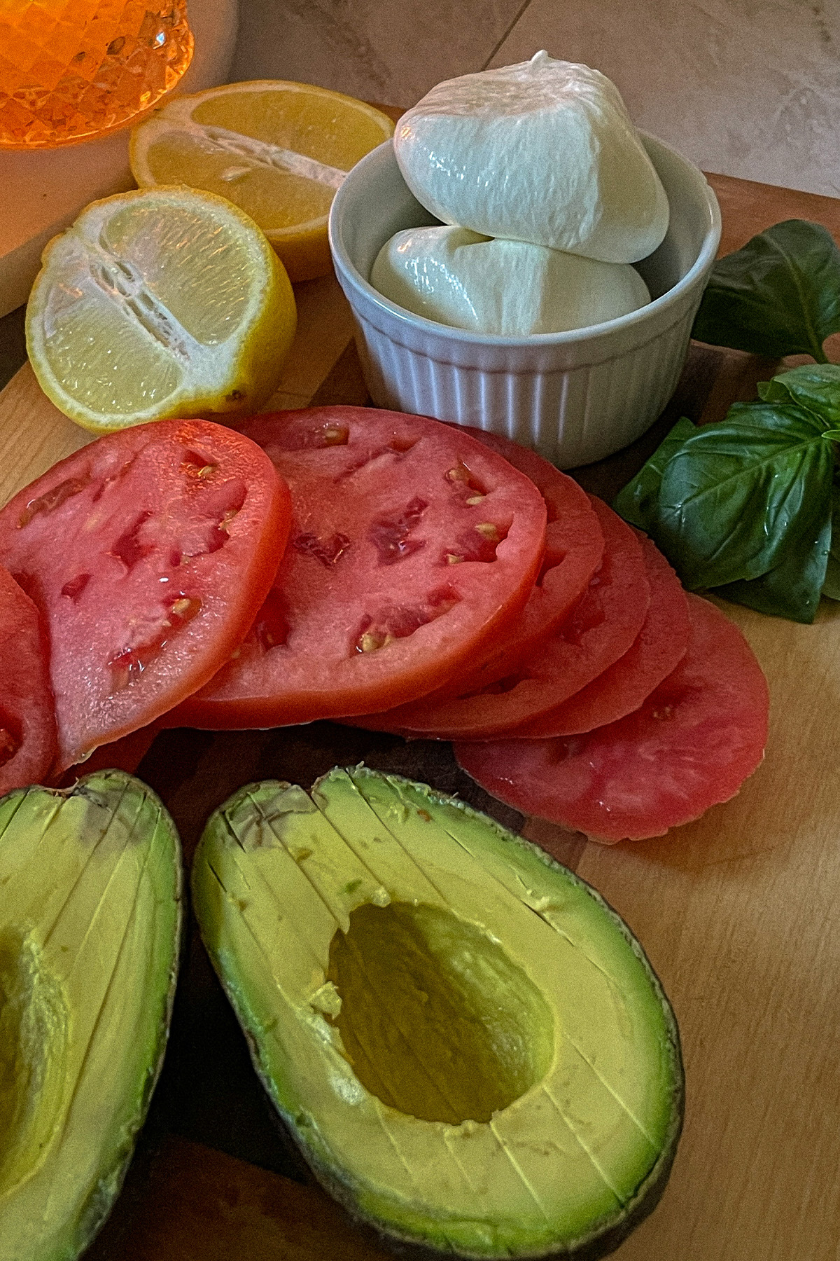 Ingredients for Easy Burrata Caprese Salad laid out on a cutting board