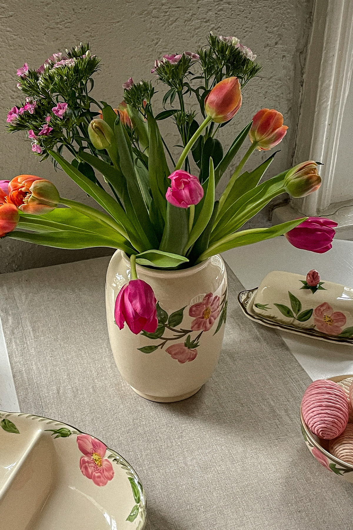 Easter table with a colorful bouquet of spring flowers in an antique vase and decorative Easter eggs