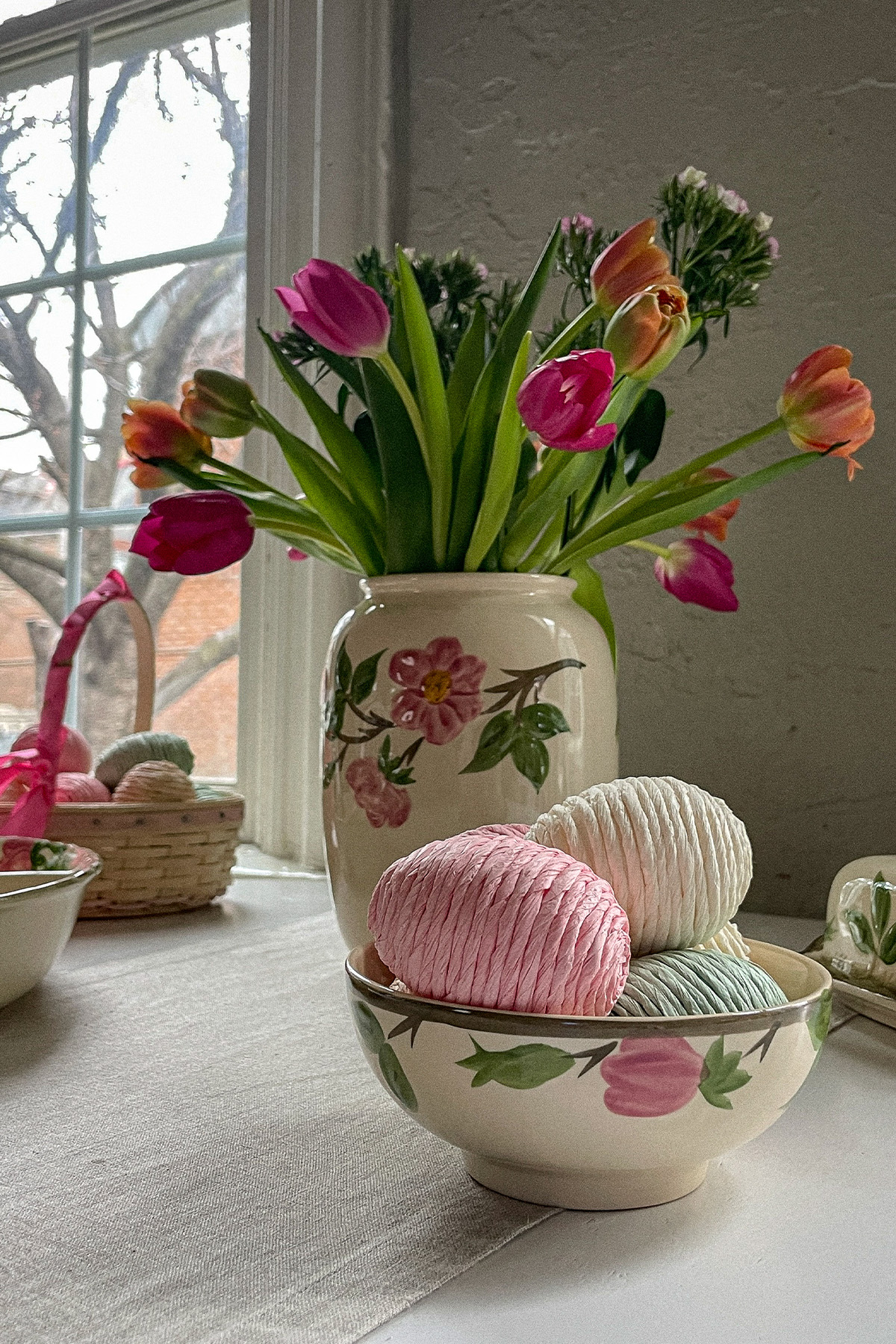 Easter table with a colorful bouquet of spring flowers in an antique vase and an Easter basket with decorative eggs