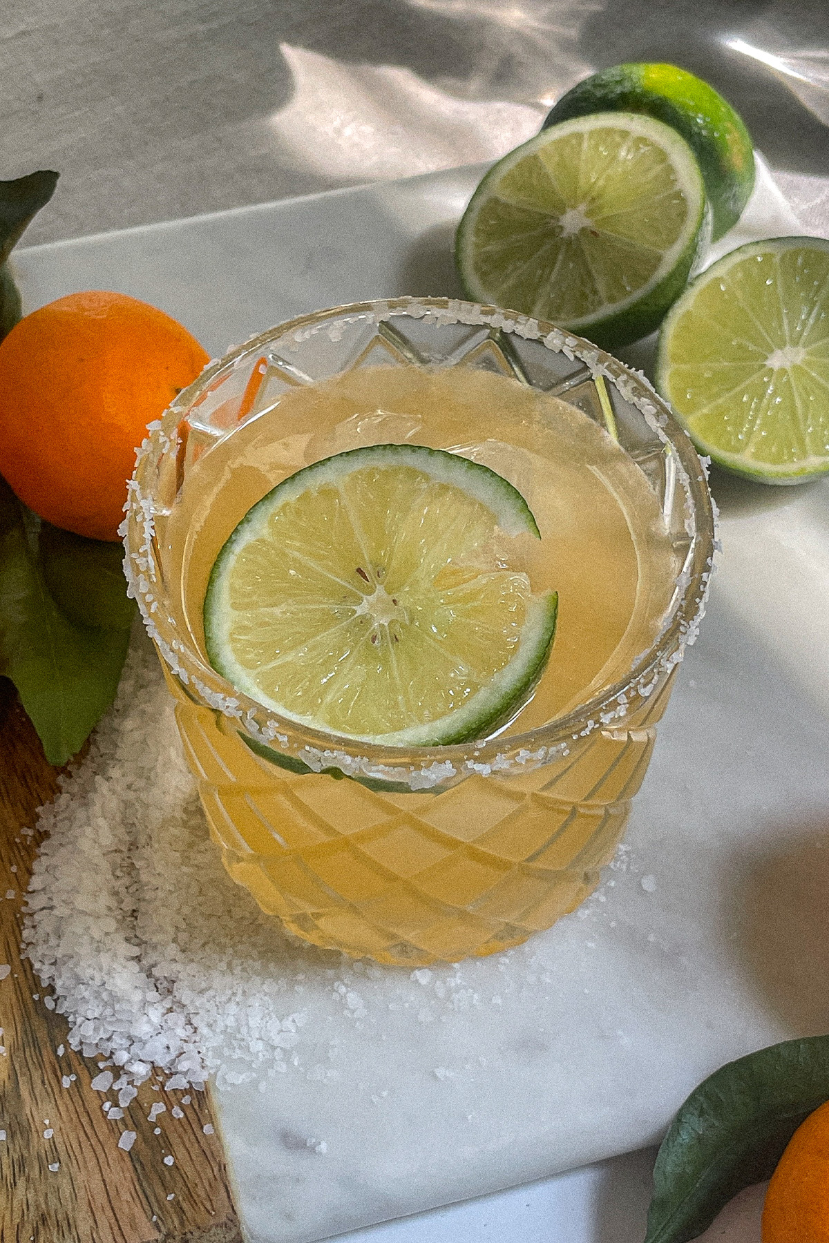 Mandarin orange margarita in a salt-rimmed glass topped with a wheel of lime