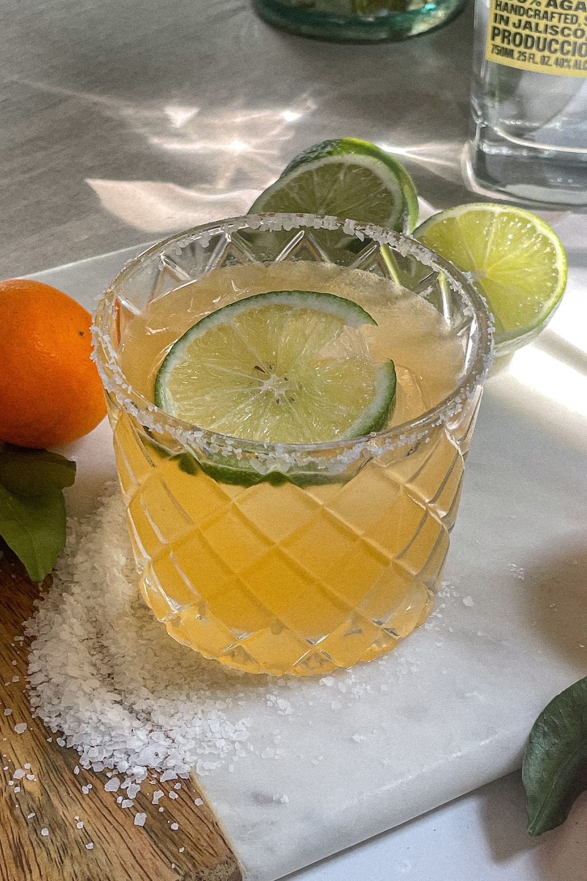 Mandarin orange margarita in a salt-rimmed glass topped with a wheel of lime