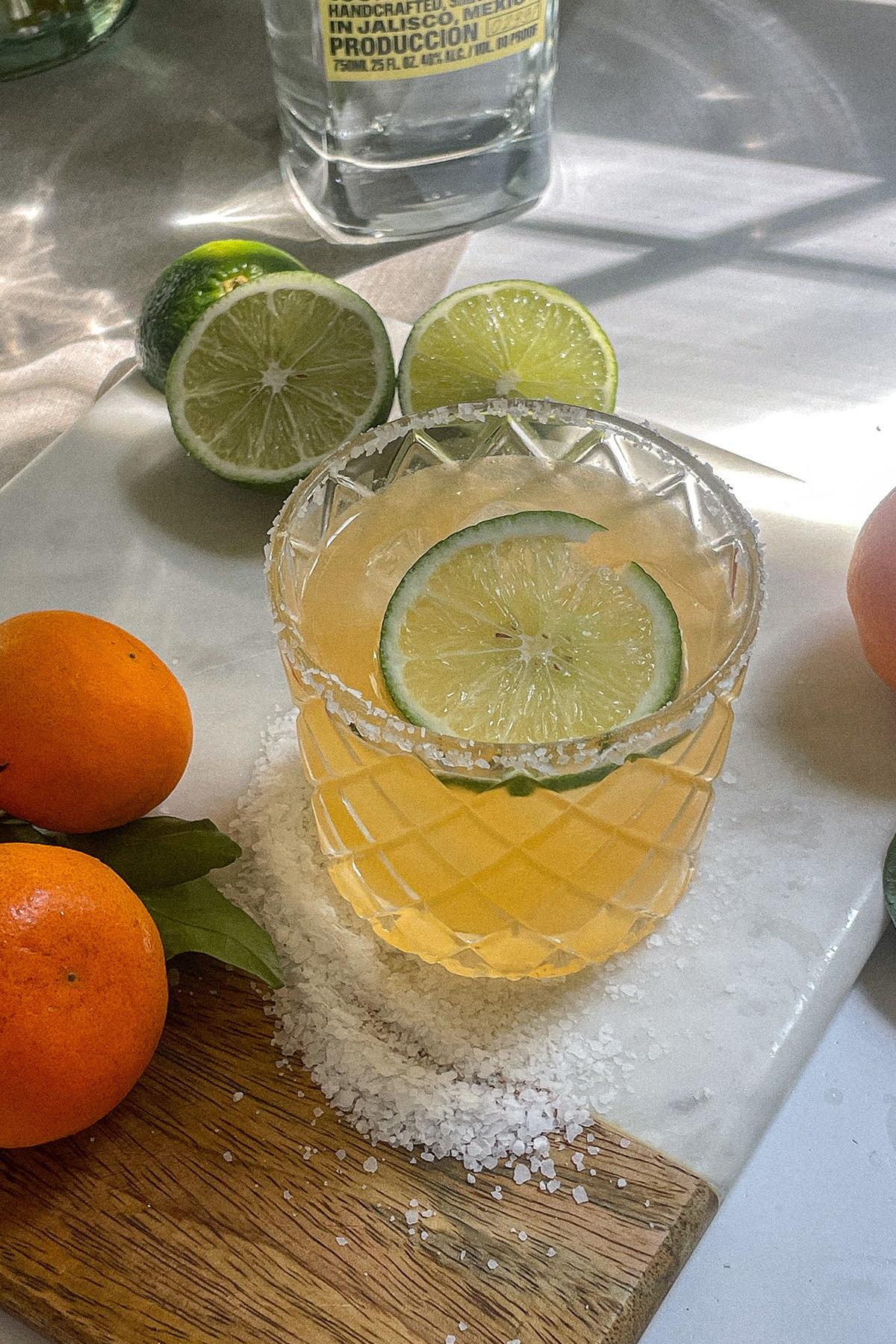 Mandarin orange margarita in a salt-rimmed glass topped with a wheel of lime