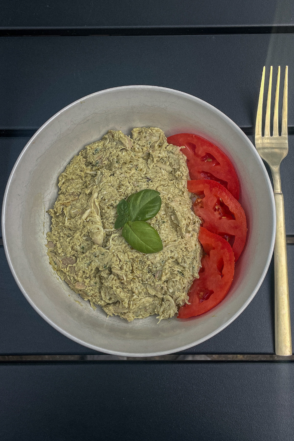 Basil Pesto Chicken Salad with sliced tomatoes and fresh basil in a bowl