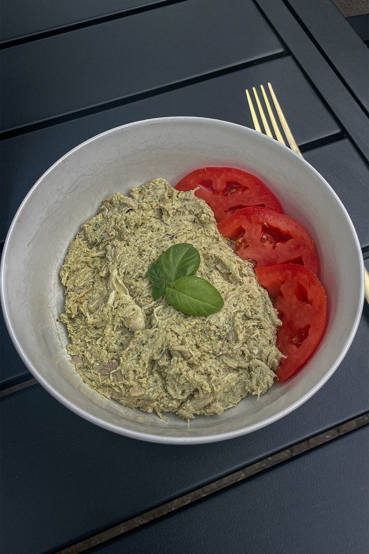 Basil Pesto Chicken Salad served with sliced tomatoes and topped with basil leaves