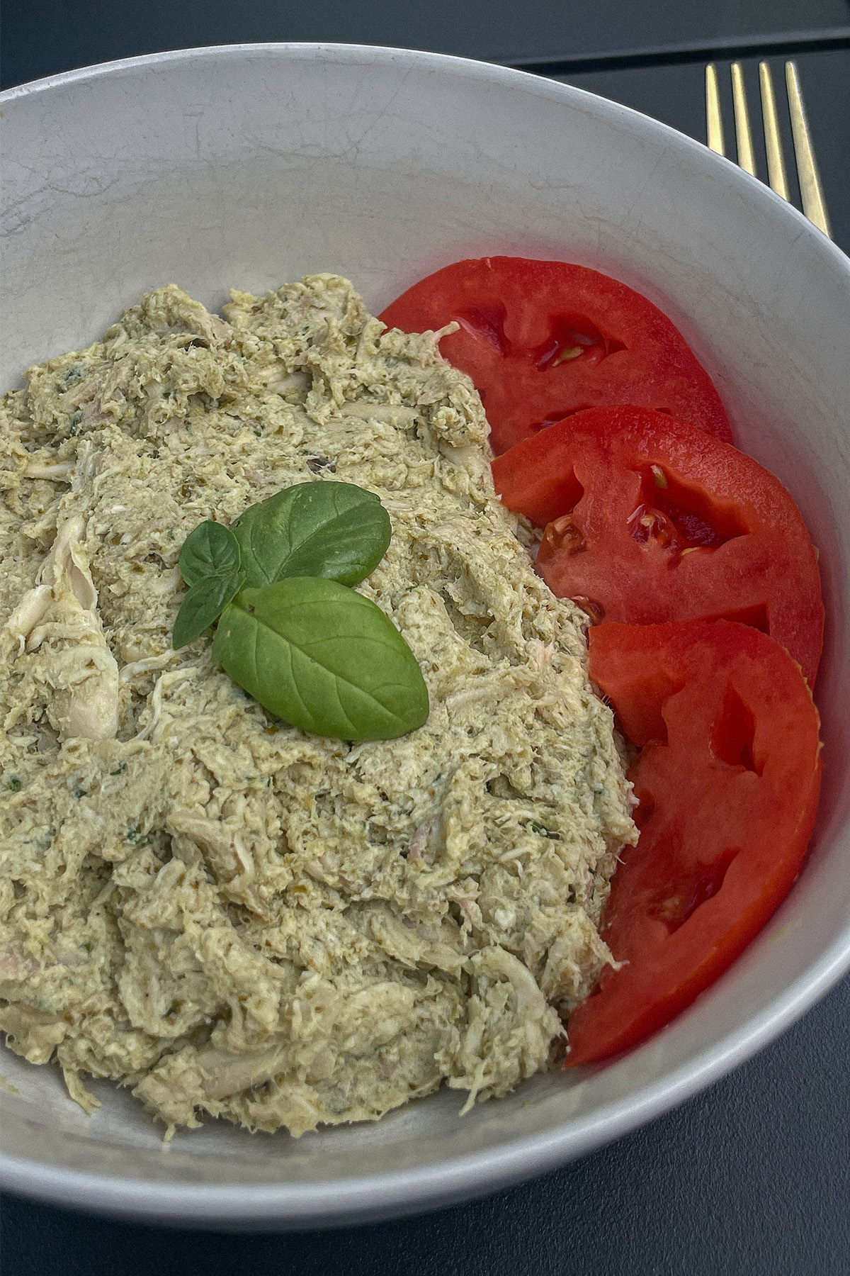 Basil Pesto Chicken Salad served with sliced tomatoes and topped with basil leaves