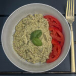 Basil Pesto Chicken Salad with sliced tomatoes and fresh basil in a bowl