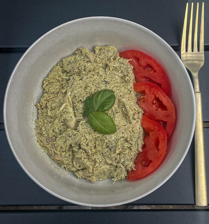 Basil Pesto Chicken Salad with sliced tomatoes and fresh basil in a bowl