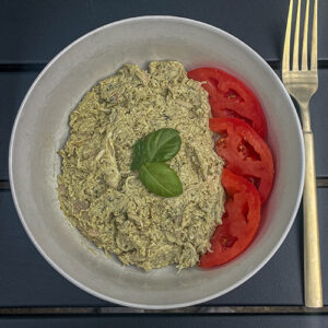 Basil Pesto Chicken Salad with sliced tomatoes and fresh basil in a bowl