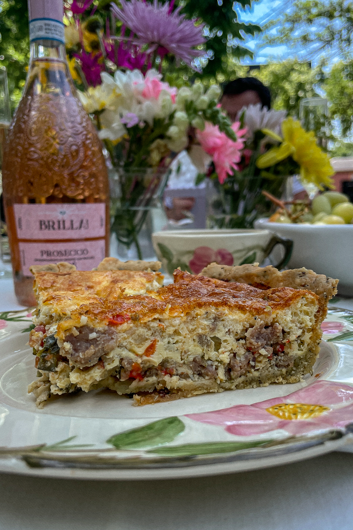 Slice of Italian Sausage Red Pepper Quiche on a pink floral plate