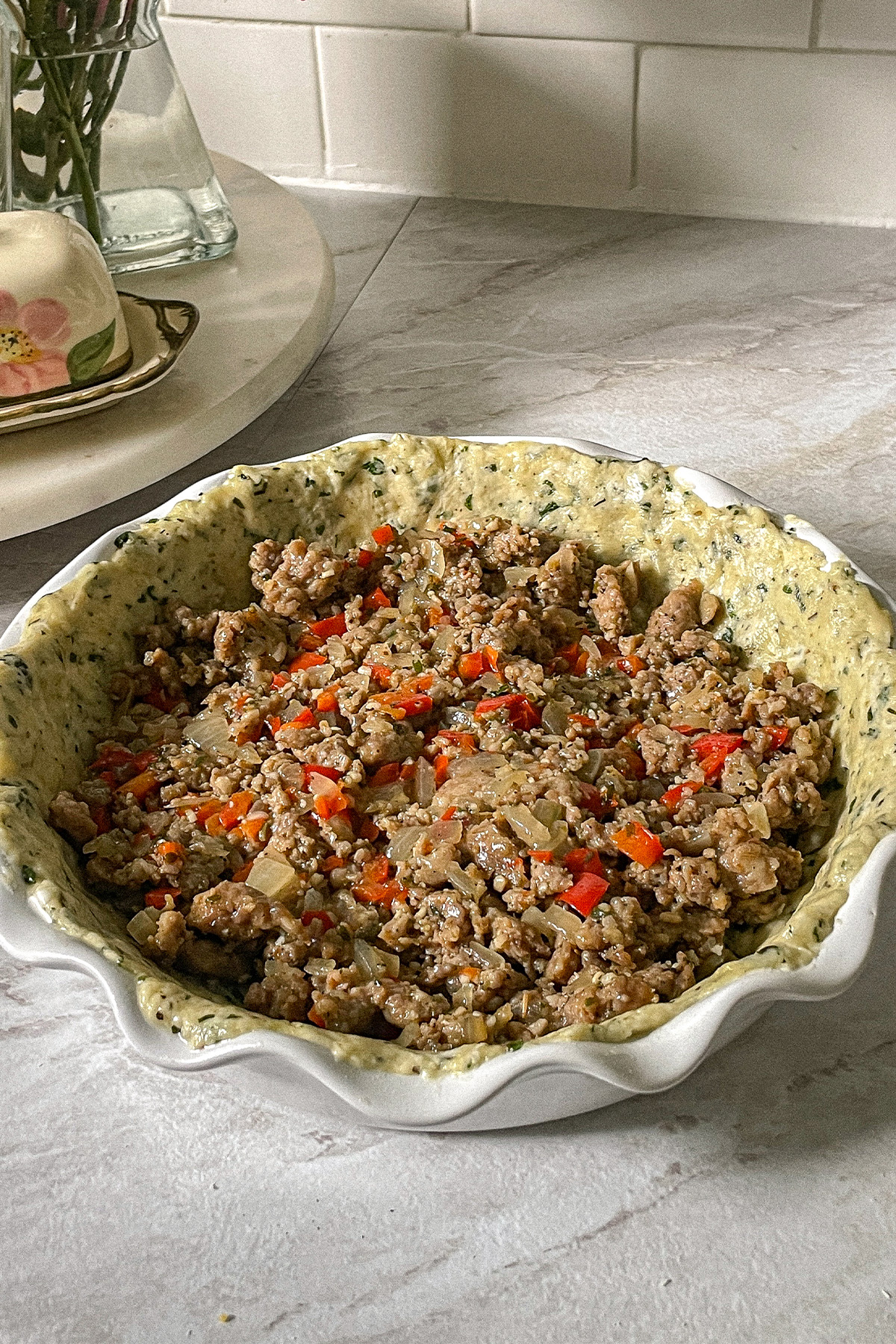 Pie pan filled with basil crust, cooked Italian sausage, red pepper and onion.