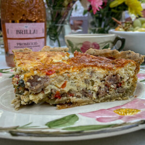 Slice of Italian Sausage Red Pepper Quiche on a pink floral plate