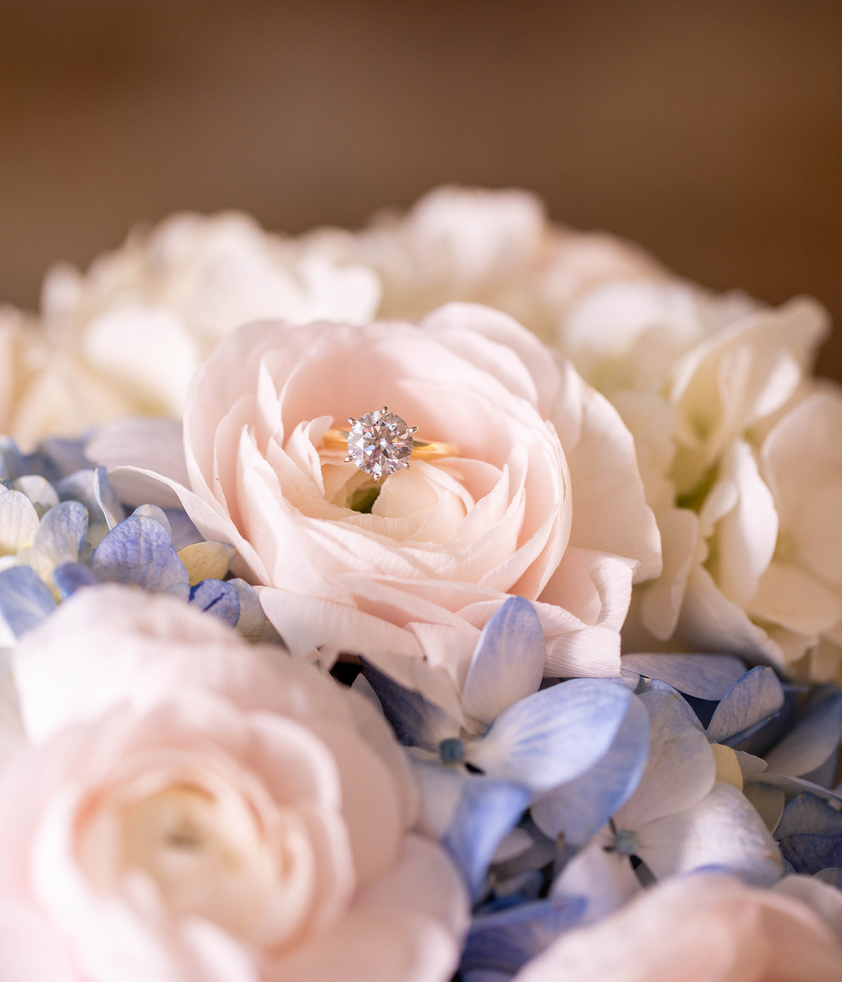 Diamond engagement ring sitting atop beautiful blue and pink wedding flowers