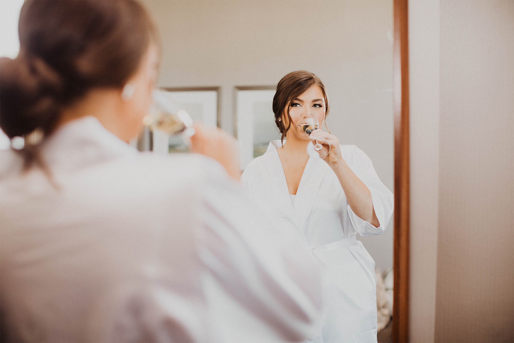 Bride sipping champagne in a white robe