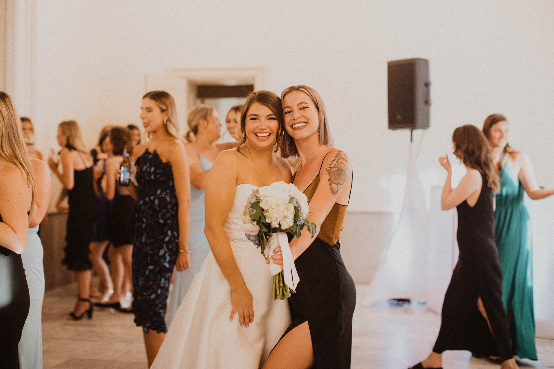 Bride posing with friend who caught the bouquet toss