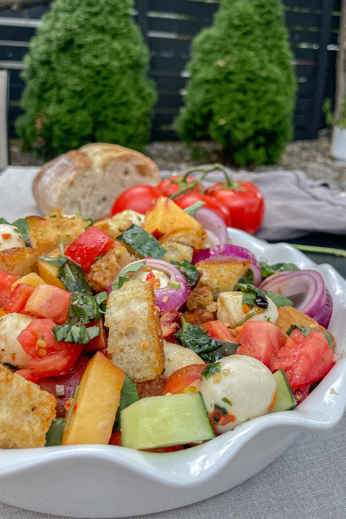 Colorful Peach Panzanella Salad in a white ruffle dish