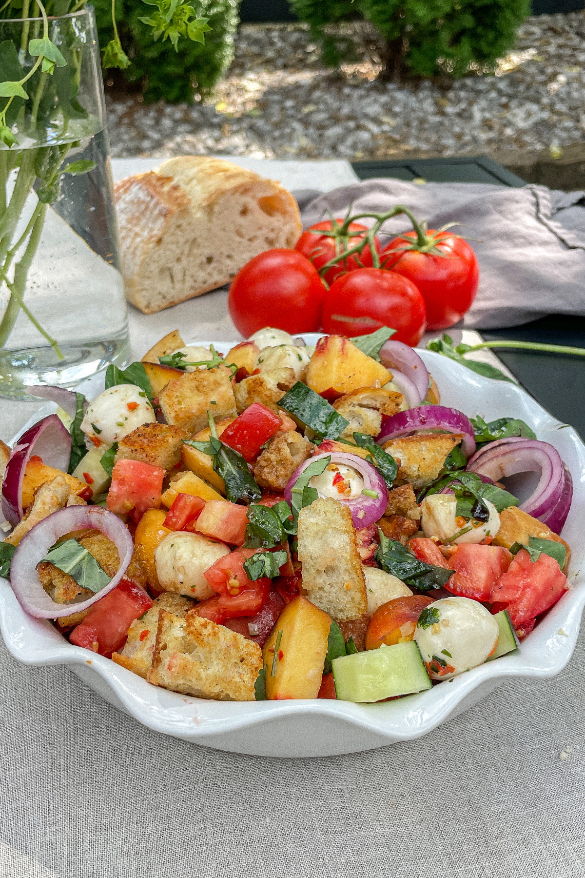 Colorful Peach Panzanella Salad in a white ruffle dish