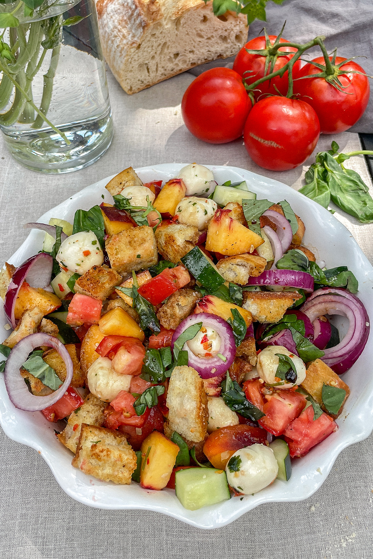 Colorful Peach Panzanella Salad in a white ruffle dish