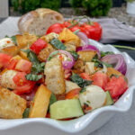 Peach Panzanella Salad in a white ruffle dish