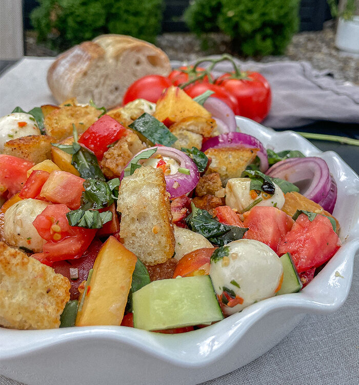 Peach Panzanella Salad in a white ruffle dish