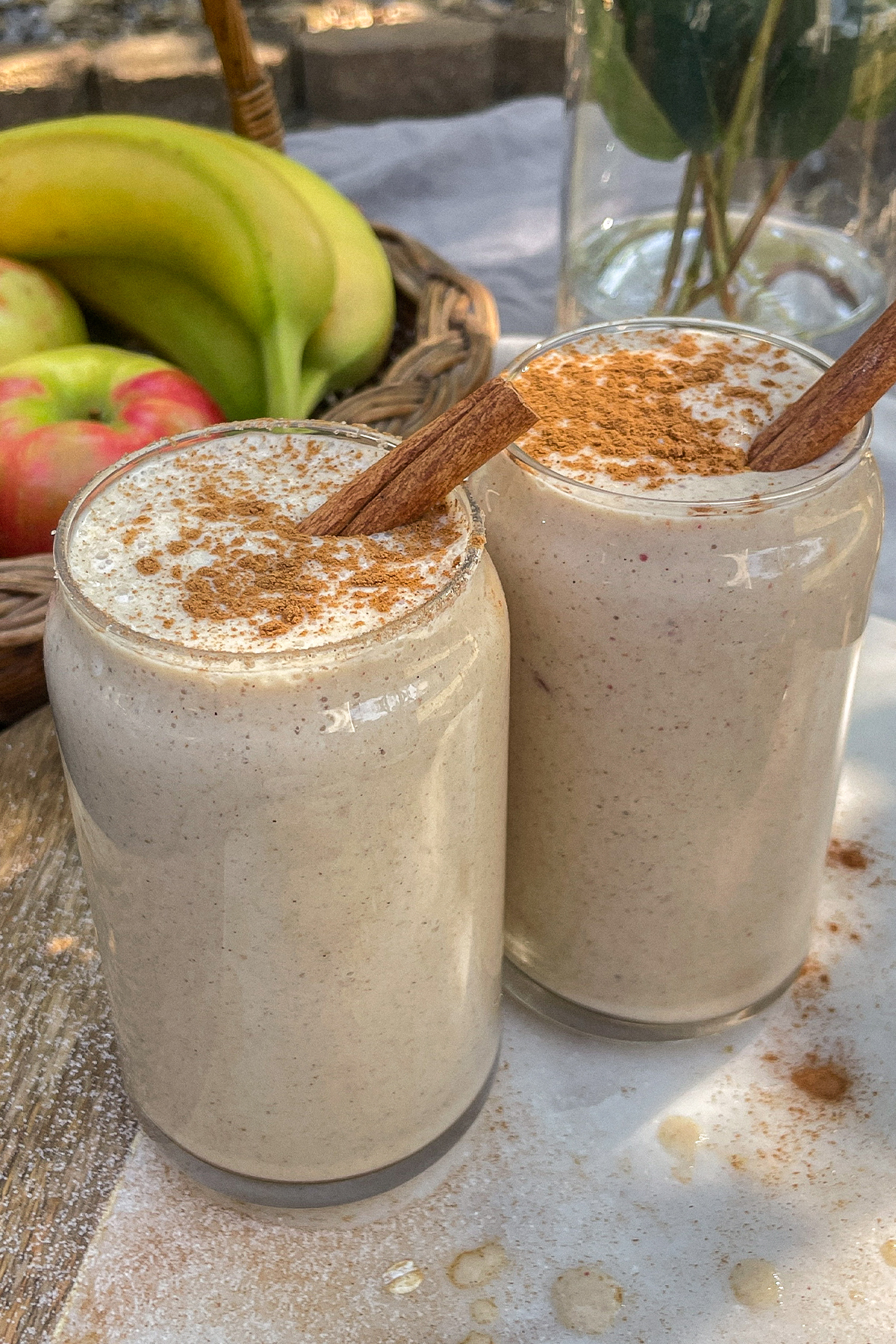 Maple Apple Crisp Smoothies served in clear glasses topped with a sprinkle of cinnamon and cinnamon sticks