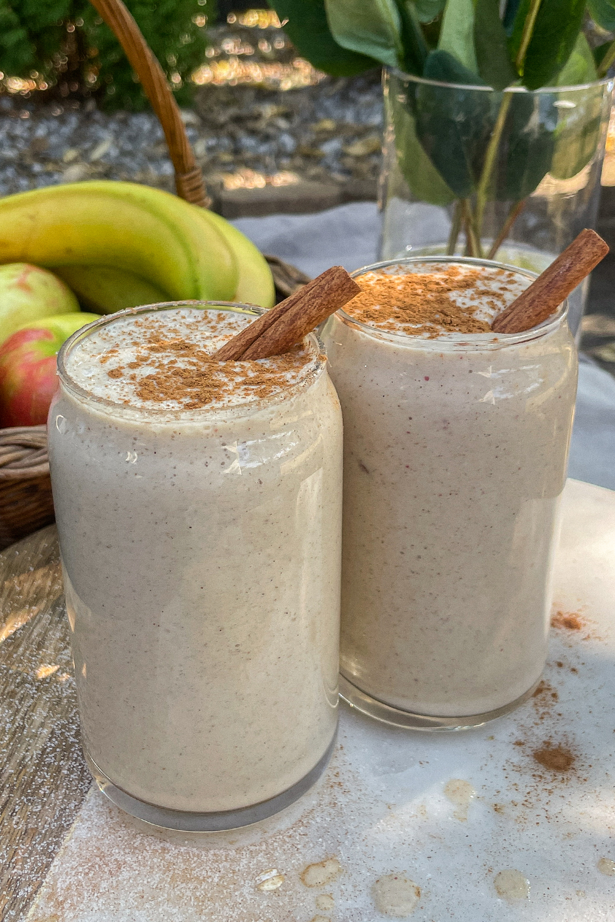 Maple Apple Crisp Smoothies served in clear glasses topped with a sprinkle of cinnamon and cinnamon sticks