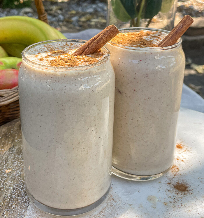 Maple Apple Crisp Smoothies served in clear glasses topped with a sprinkle of cinnamon and cinnamon sticks