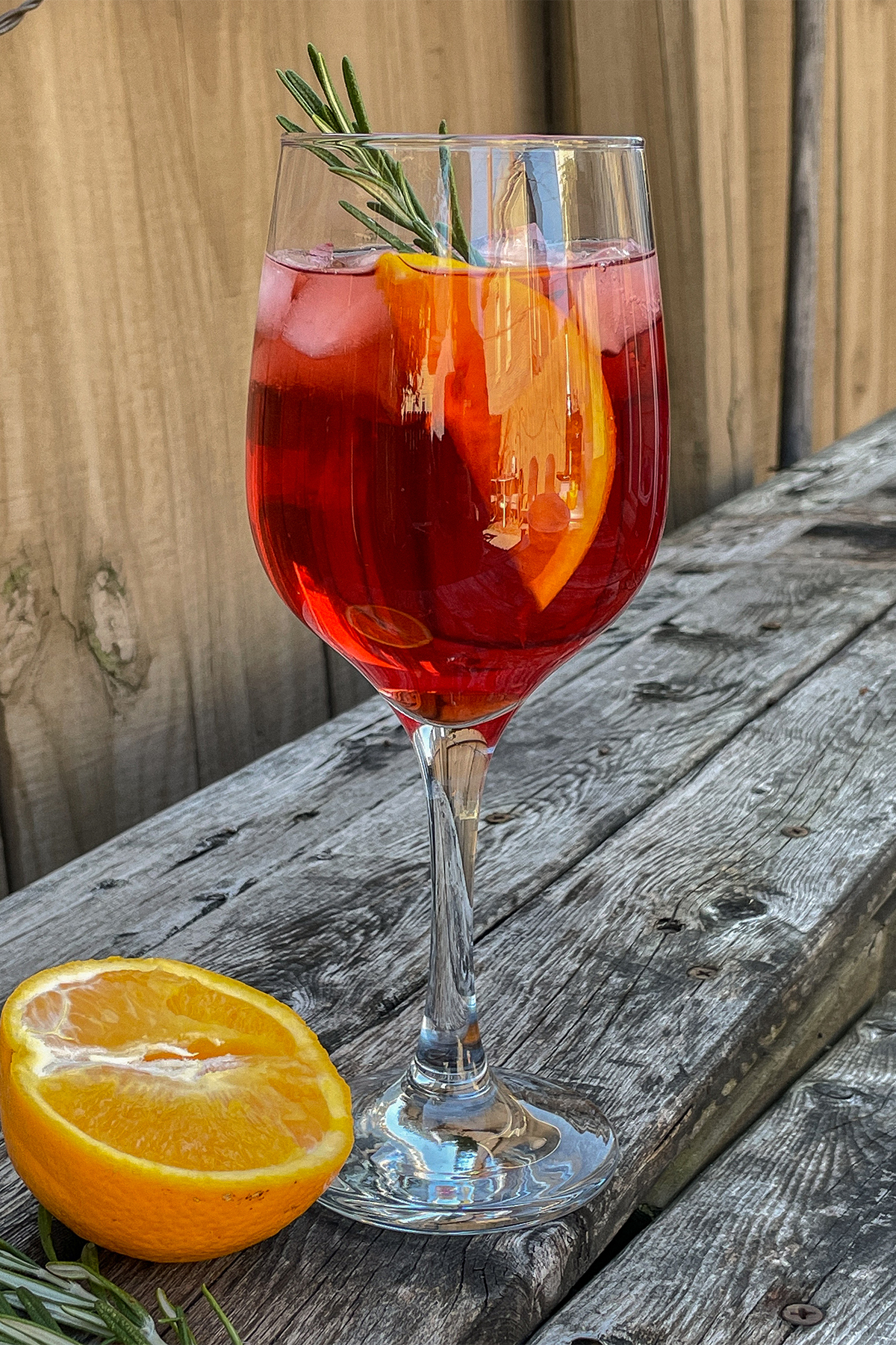 Cranberry Aperol Spritz served in a wine glass and garnished with an orange slice and rosemary sprig