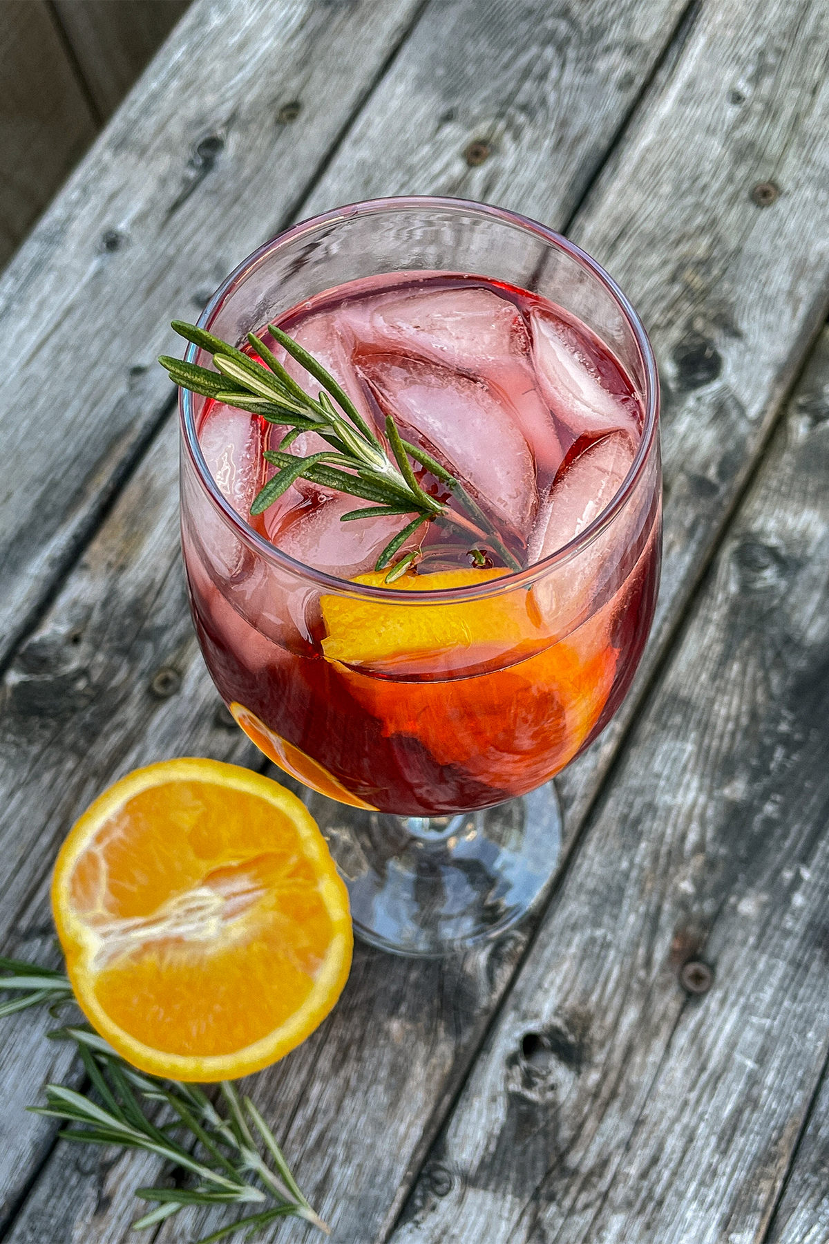 Cranberry Aperol Spritz served in a wine glass and garnished with an orange slice and rosemary sprig