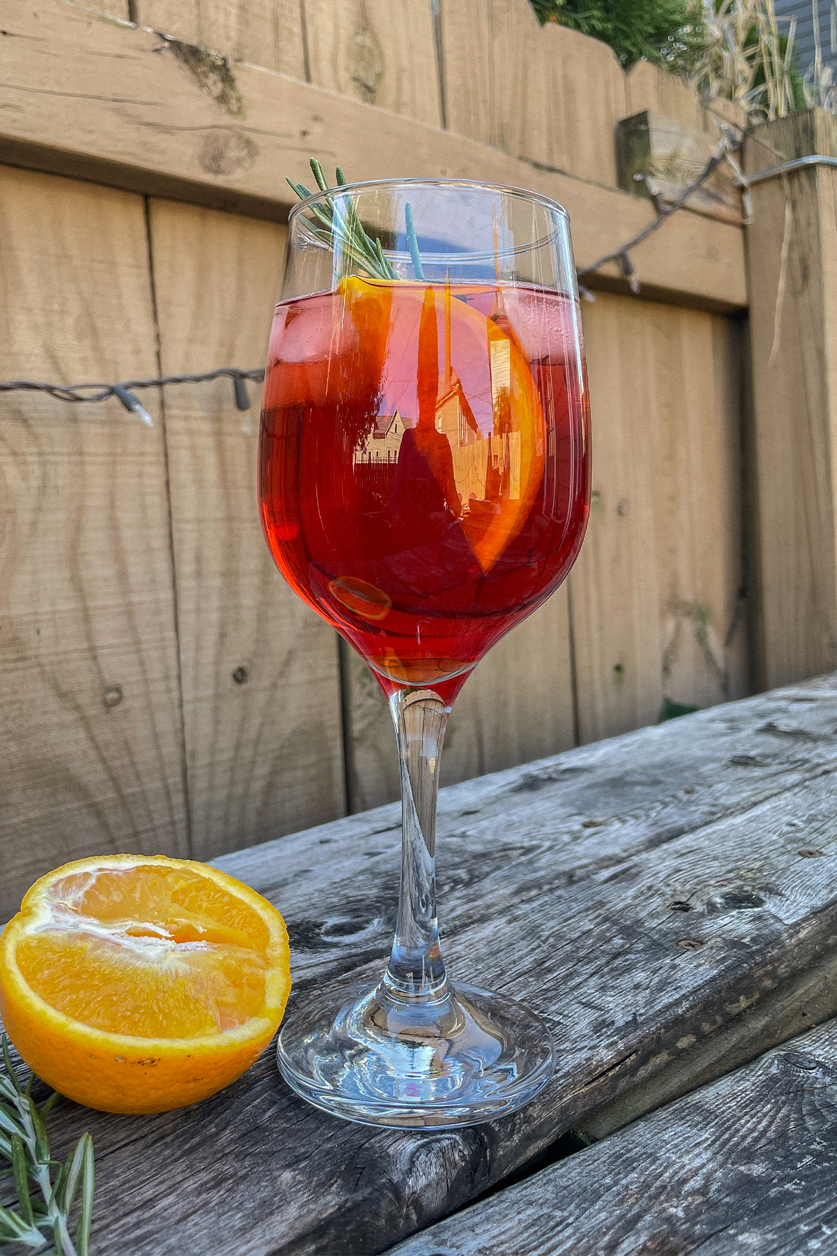 Cranberry Aperol Spritz served in a wine glass and garnished with an orange slice and rosemary sprig