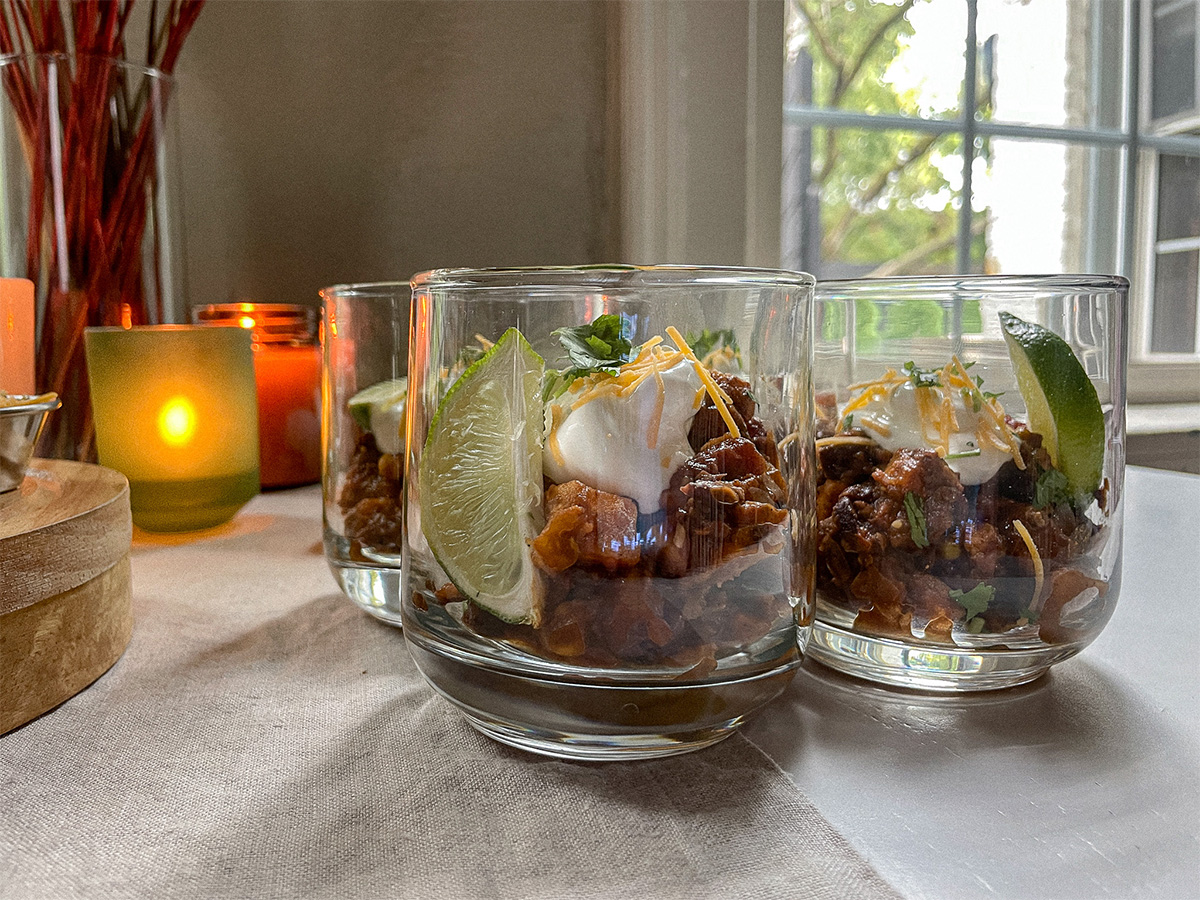 Southwest Sweet Potato Chili served in glass cups topped with sour cream, cheese, cilantro and a lime wedge