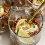 Southwest Sweet Potato Chili served in glass cups topped with sour cream, cheese, cilantro and a lime wedge