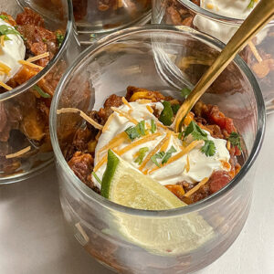 Southwest Sweet Potato Chili served in glass cups topped with sour cream, cheese, cilantro and a lime wedge