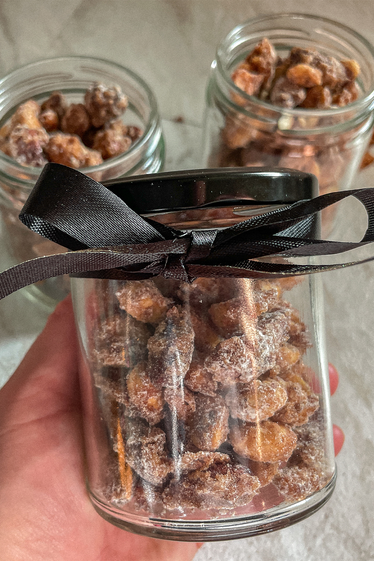 Jar of homemade candied nuts with a black bow tied around it