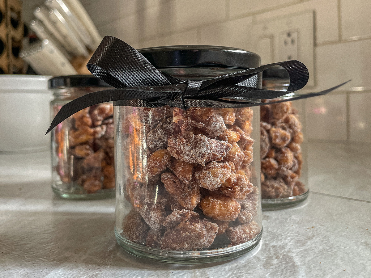 Jar of homemade candied nuts with a black bow tied around it