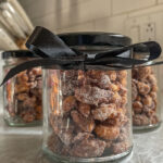 Jar of homemade candied nuts with a black bow tied around it