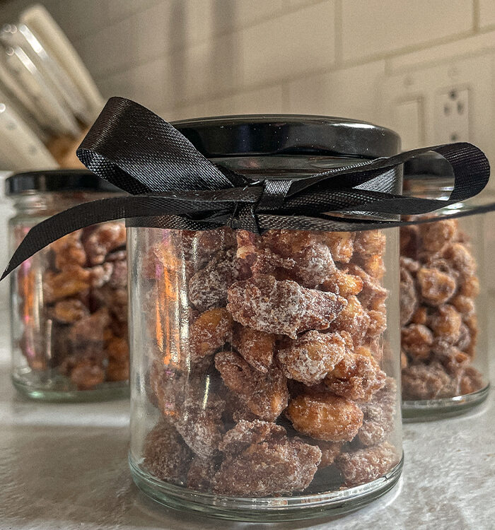 Jar of homemade candied nuts with a black bow tied around it