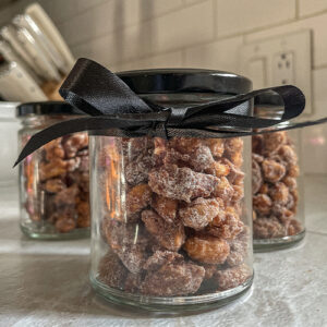 Jar of homemade candied nuts with a black bow tied around it