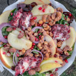 Kale Apple Salad With Cranberry Goat Cheese served in a white ruffle pie dish